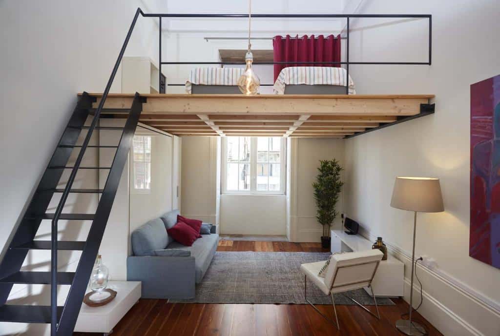 Sala do The Passenger Hostel, no Porto, com sofá e poltrona e uma escada de acesso a um quarto com duas camas