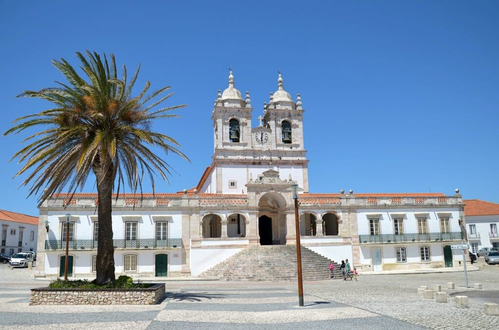A Igreja de Nossa Senhora da Nazaré, com fachada imponente e duas torres sineiras simétricas, na praça de calçada portuguesa.