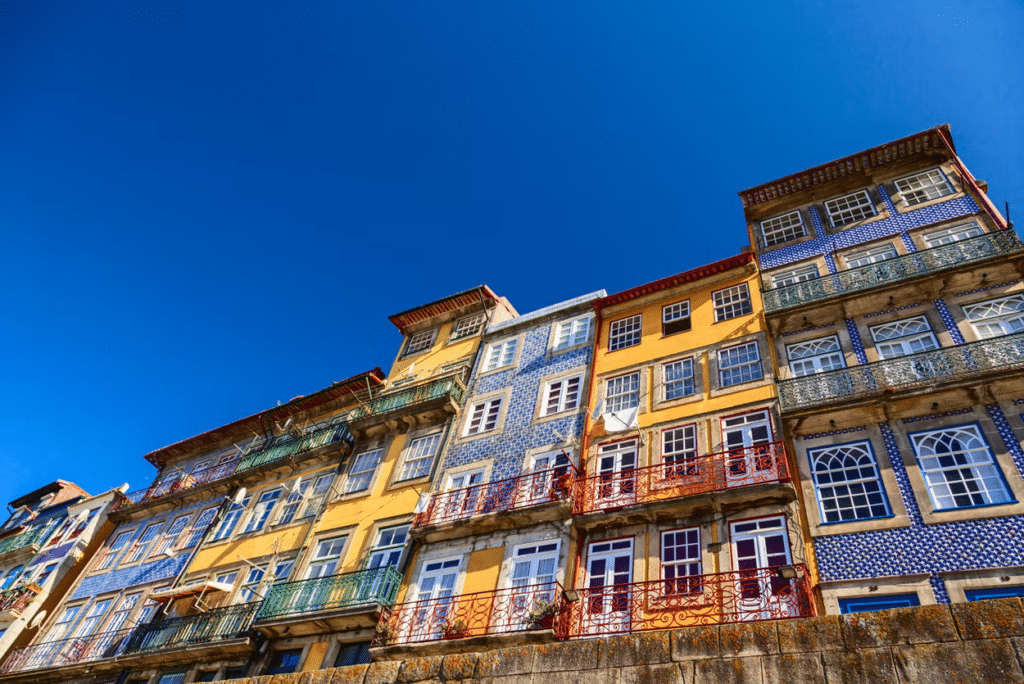 Fachadas de edifícios históricos coloridos com azulejos e varandas de ferro forjado na Ribeira do Porto